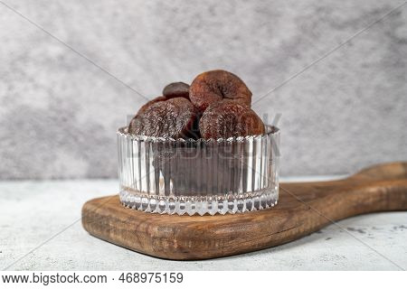 Dried apricots on stone background. Dark dried apricots in a glass bowl. Diet foods. close up