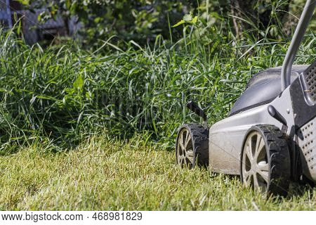 Mowing The Lawn With An Electric Lawn Mower. A Fragment Of The Wheels Of An Electric Lawn Mower And 