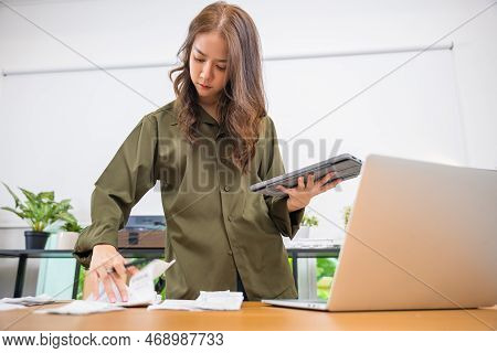 Asian Young Woman Working With Financial Data She Calculator With Tablet Computer And Writing Make N