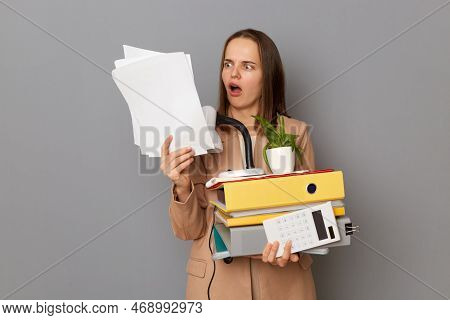 Indoor Shot Of Shocked Surprised Woman Wearing Stylish Beige Jacket Holding Office Stuff Posing Isol