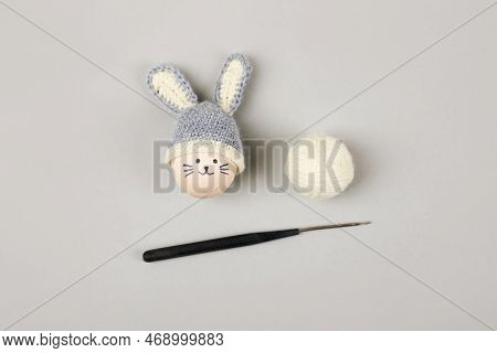 Easter Egg With Funny Face And Gray Crocheted Hat With Bunny Ears With A Balls Of Thread And A Croch
