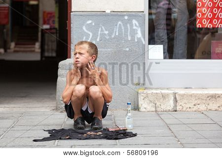 SARAJEVO, BOSNIA AND HERZEGOVINA - AUG 11: Sevdalija Osmanovic, 10 years old, sings on street to bypassers on August 11, 2012 in Sarajevo, B&H. He sings in order to provide money for his family.