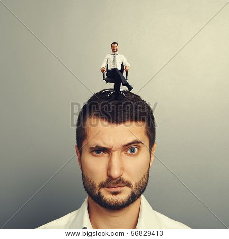 portrait of displeased man with small happy man on the head