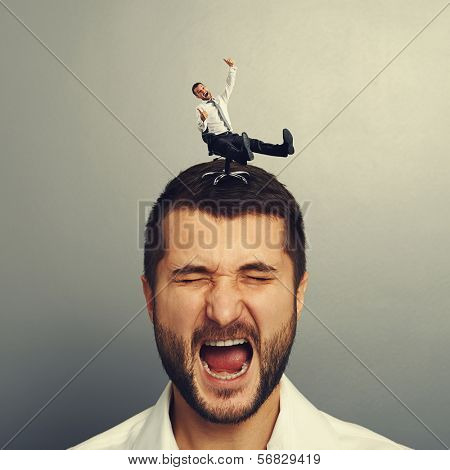 portrait of displeased screaming man with small happy man on the head