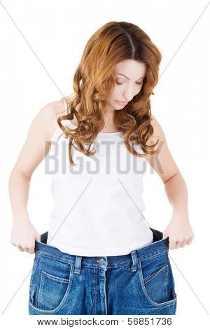 Happy fit woman with big pants, showing how much weight she lost.