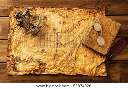 Sextant, old book and glasses on vintage map over wooden background 