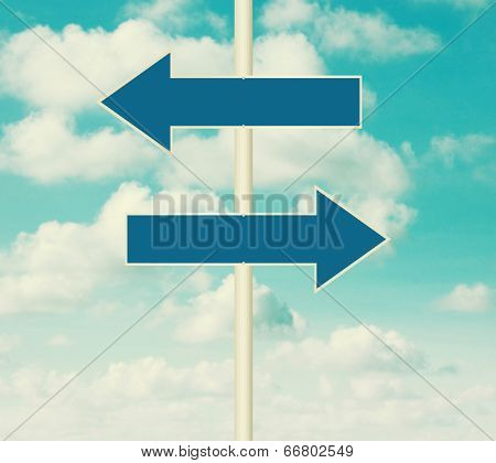 Two blank road signs pointing in opposite directions, blue sky background in vintage style.