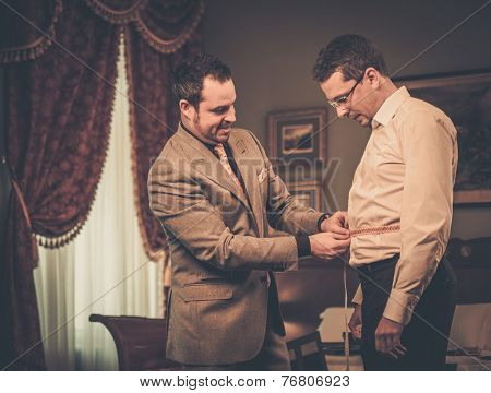 Tailor measuring client for custom made suit tailoring 