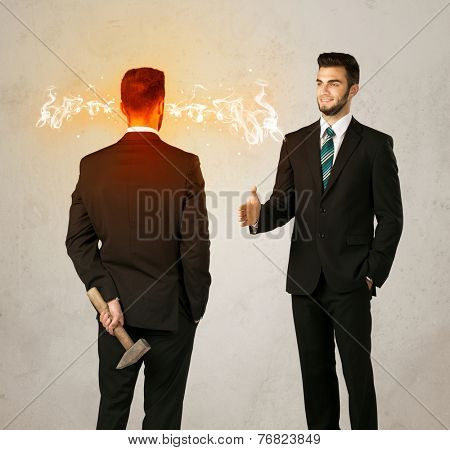 Angry businessman hiding a weapon behind his back 