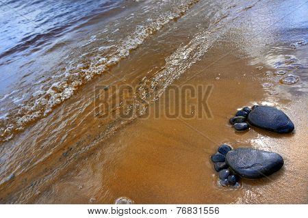 pair of feet made from pebbles on the sea sand  texture surface backdrop                       