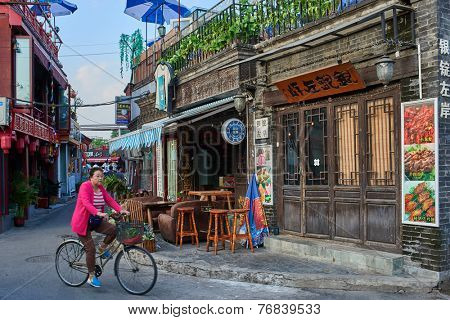 Beijing , China - September 24, 2014:  Chinese woman cycling in traditional Hutong streets Beijing China