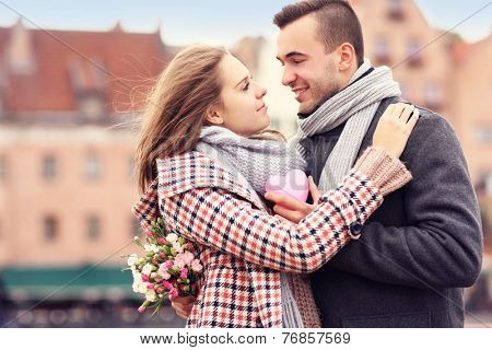A picture of a couple on Valentine's Day in the city with flowers and heart