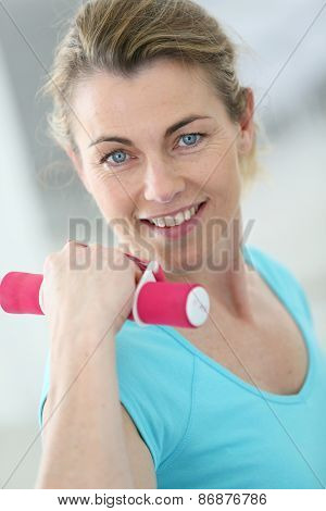 Portrait of mature fitness woman lifting dumbbells