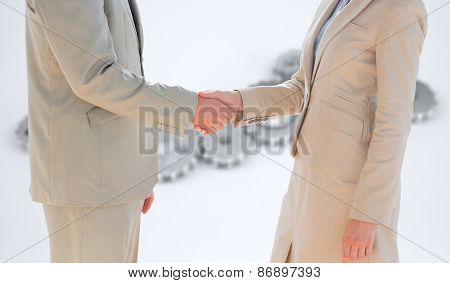 Business people shaking hands against cogs and wheels