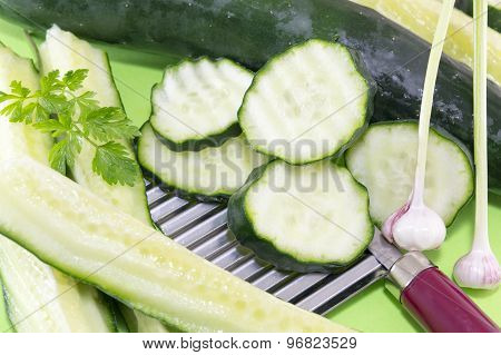 Sliced Cucamber And Marrow Squash  Ordered On Top Of The Chopper On Green Background
