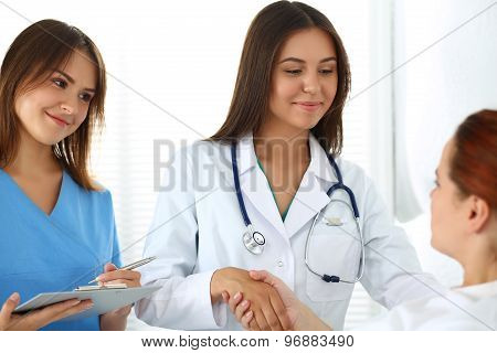Female Doctor Shaking Hands With Patient Lying In Bed