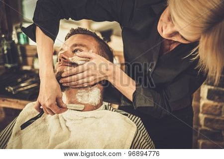 Client during beard shaving in barber shop