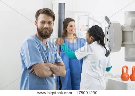 Confident Male Radiologist With Colleague And Patient In Backgro