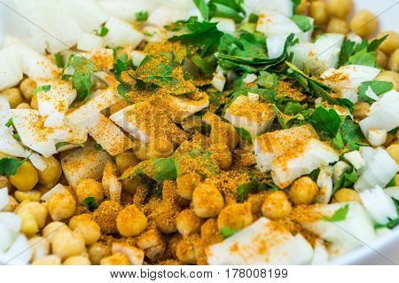 Cheakpeas with garam masala spices, onions and leaves of parsley. Close-up image of cooked chickpeas, chopped onion, garlic and fresh parsley in bowl seasoned with indian curry spices
