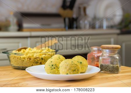 Falafel balls and minced cheakpeas on the table. Uncooked falafel with glasses of spices on wood table in front of kitchen background