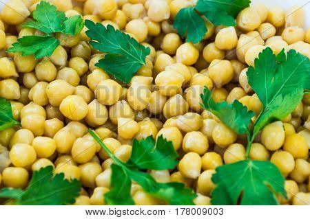 Cheakpeas and leaves of parsley. Close-up image of cooked chickpeas and fresh parsley in bowl