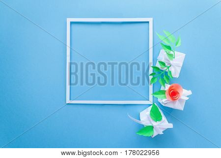 square frame with white gift with color paper flower on blue background