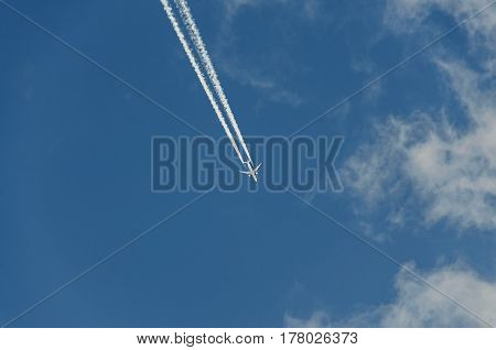 Airplane With Reaction Trail Flying Over Blue Sky With Clouds, Close Up