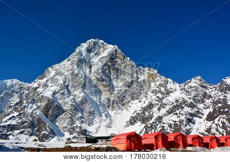 Row of the red tents way from Cho-La pass to the Everest base camp Nepal. Magnificent Himalayan mountains on the background.