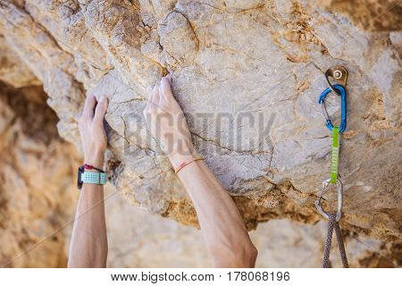 Closeup of climber's hands on cliff beside bolt with clipped quickdraw and rope