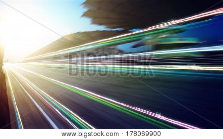 Foward motion speed lens blur racing circuit background with seated stand sunset scene and light trail effect .