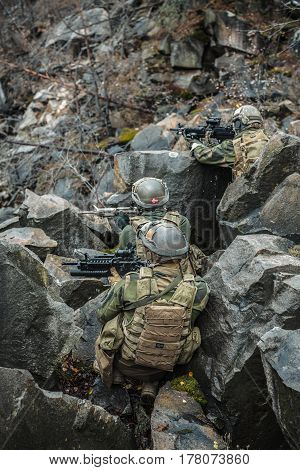 Patrol of norwegian Rapid reaction special forces FSK soldiers in field uniforms in ambush among the rocks guarding perimeter waiting enemy