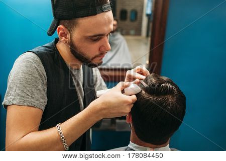 Young barber cut man hair free space. Professional hairtician making hairdo for brunet, sitting at mirror. Beauty, barbershop, occupation, style, modern life concept