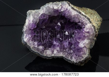 An attractive amazing mineral  big amethyst druse on a black glossy surface, from a personal collection of semi-precious stones and minerals