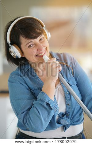Cheerful overweigth woman having fun sweeping the floor