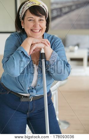 Cheerful overweigth woman having fun sweeping the floor