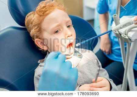 Young scared boy during the dental procedure at the dental office