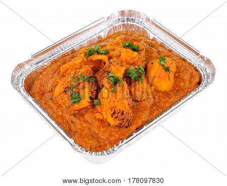 Creamy chicken tikka masala curry in a foil take away tray isolated on a white background