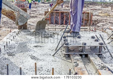 Workers at building site are pouring concrete in mold from mixer truck.