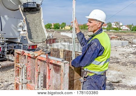 Zrenjanin Vojvodina Serbia - April 30 2015: Construction worker is holding leveling rod to help surveyor geodesist to measure position depth.
