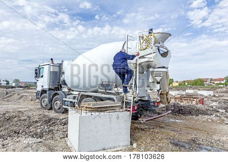 Driver is washing mixer truck with water jet after concrete casting.