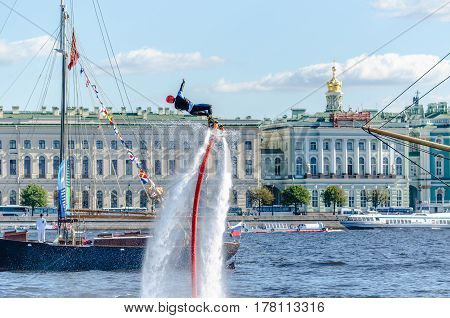 Athlete flavorlist performs pirul over the Neva river on the background of the waterfront, buildings, Cathedral and blue sky. St. Petersburg, summer, 2015.