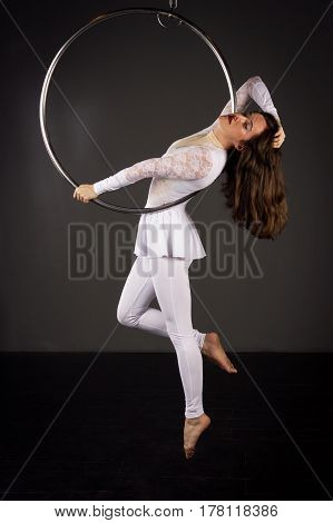 Attractive aerialist woman exercising on aerial ring (lyra)