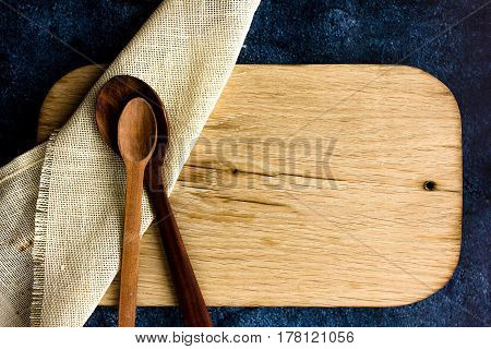 Rural kitchen board  With wooden spoons and old weave from above - grunge background with free text space. concrete background.  Different stuff. Top view. Copy space.