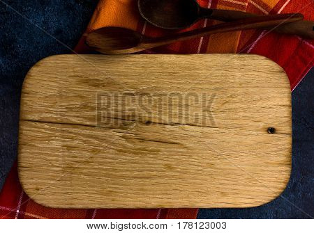 Rural kitchen board  With wooden spoons and old red cloth from above - grunge background with free text space. concrete background.  Different stuff. Top view.
