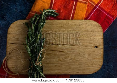 Rural kitchen board  With rosemary and old red cloth from above - grunge background with free text space. concrete background.  Different stuff. Top view.