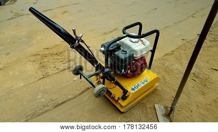 Vibratory plate compactor under construction and background