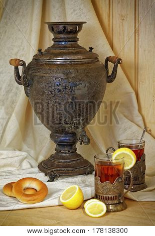 Russian samovar, tea with lemon in faceted glasses with cup holders and bublik. Tinted photo in vintage style.