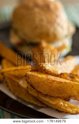 Depth of field photo of burger and hand cut fries on a plate.