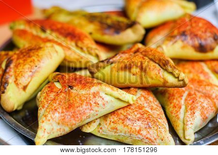 Cooked patties lie on a metal plate sprinkled with red spices