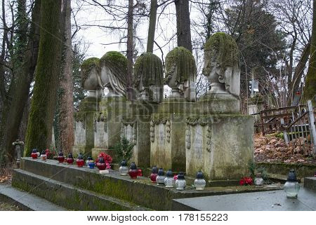 LVIV UKRAINE - JANUARY 6 2014: An alley at Lychakiv cemetery (Lviv Ukraine) and old tombstones covered with moss on winter cloudy day.